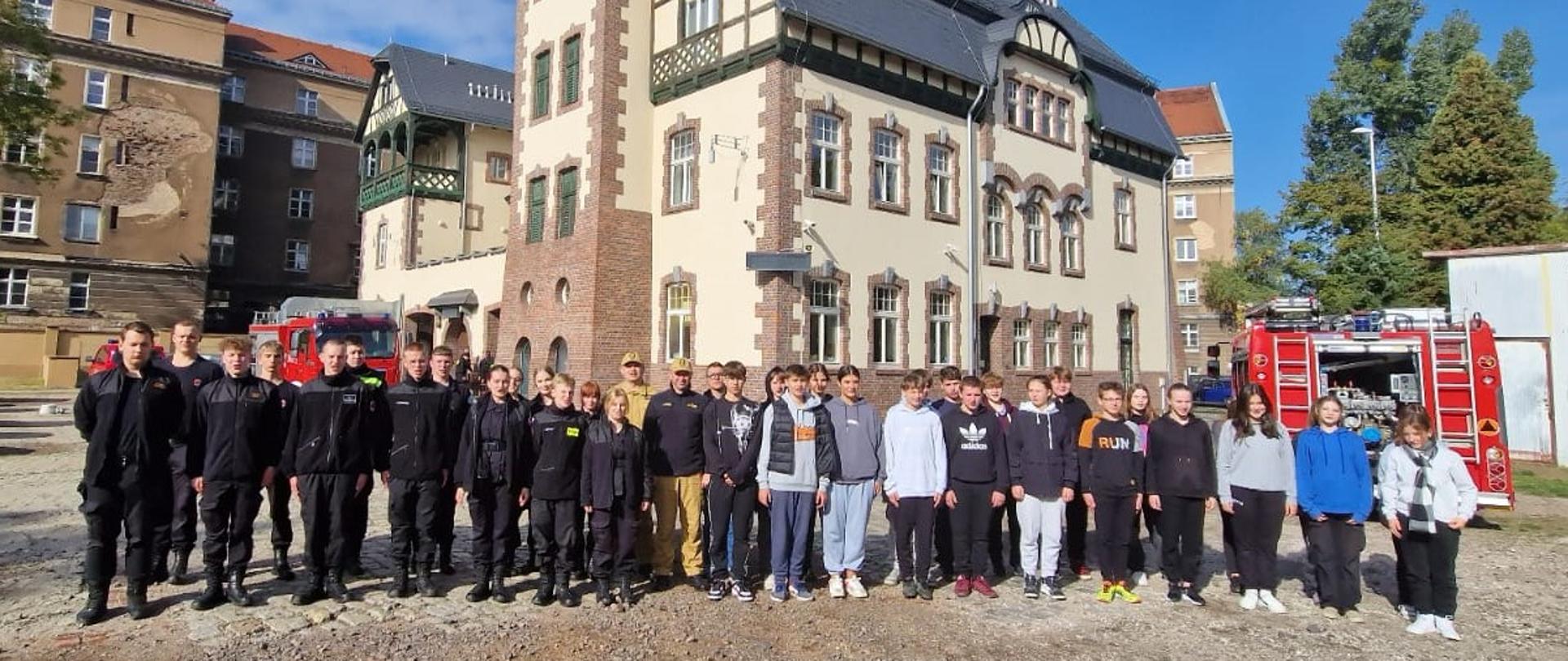 Grupowe zdjęcie uczestników szkolenia z dowódcami JRG na tle jednostki ratowniczo gaśniczej nr 2