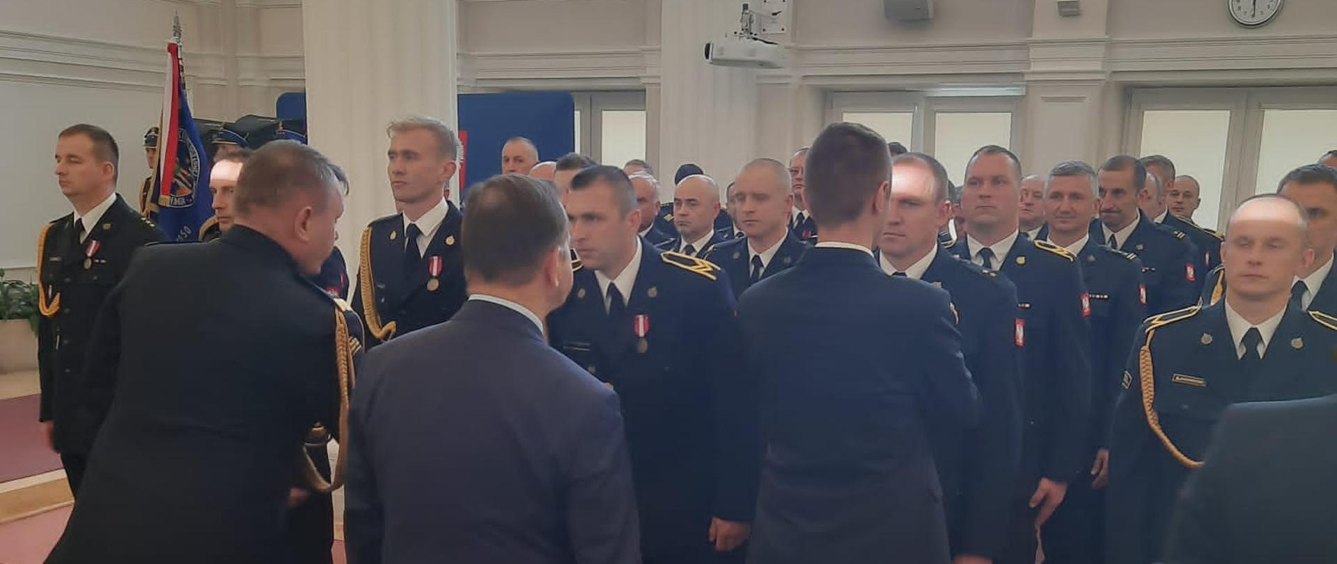 Zdjęcie przedstawia st. ogn. Tomasza Galanta podczas odznaczenia „Brązowym Medalem Za Długoletnią Służbę”.