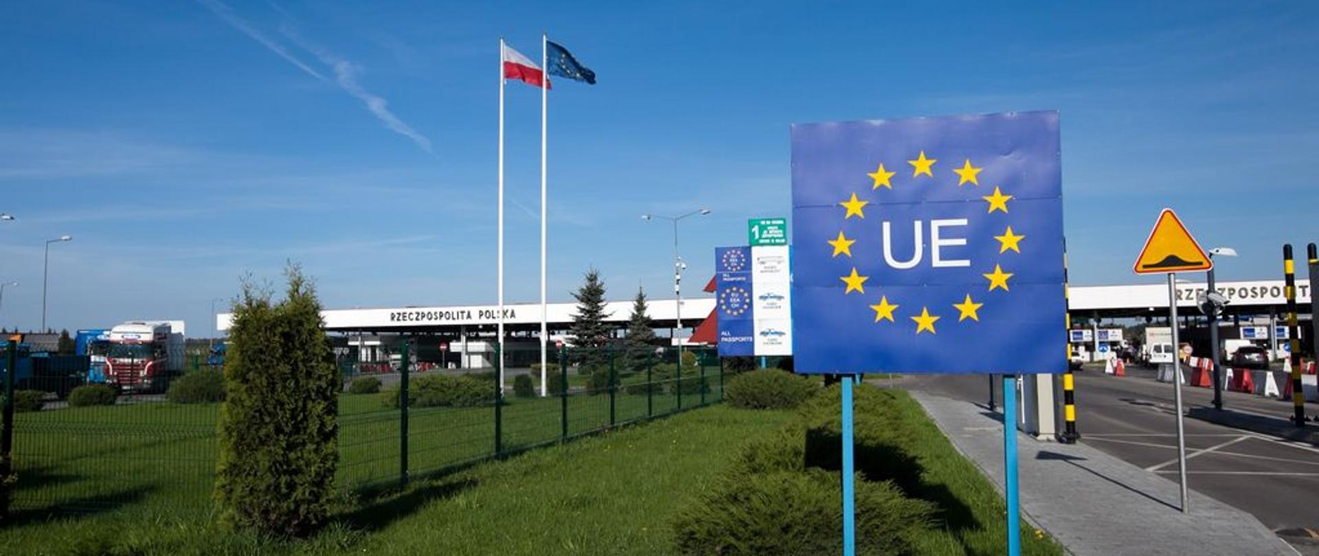 Przejście graniczne, tablica z symbolem UE, flagi Rzeczypospolitej Polskiej i Unii Europejskiej.