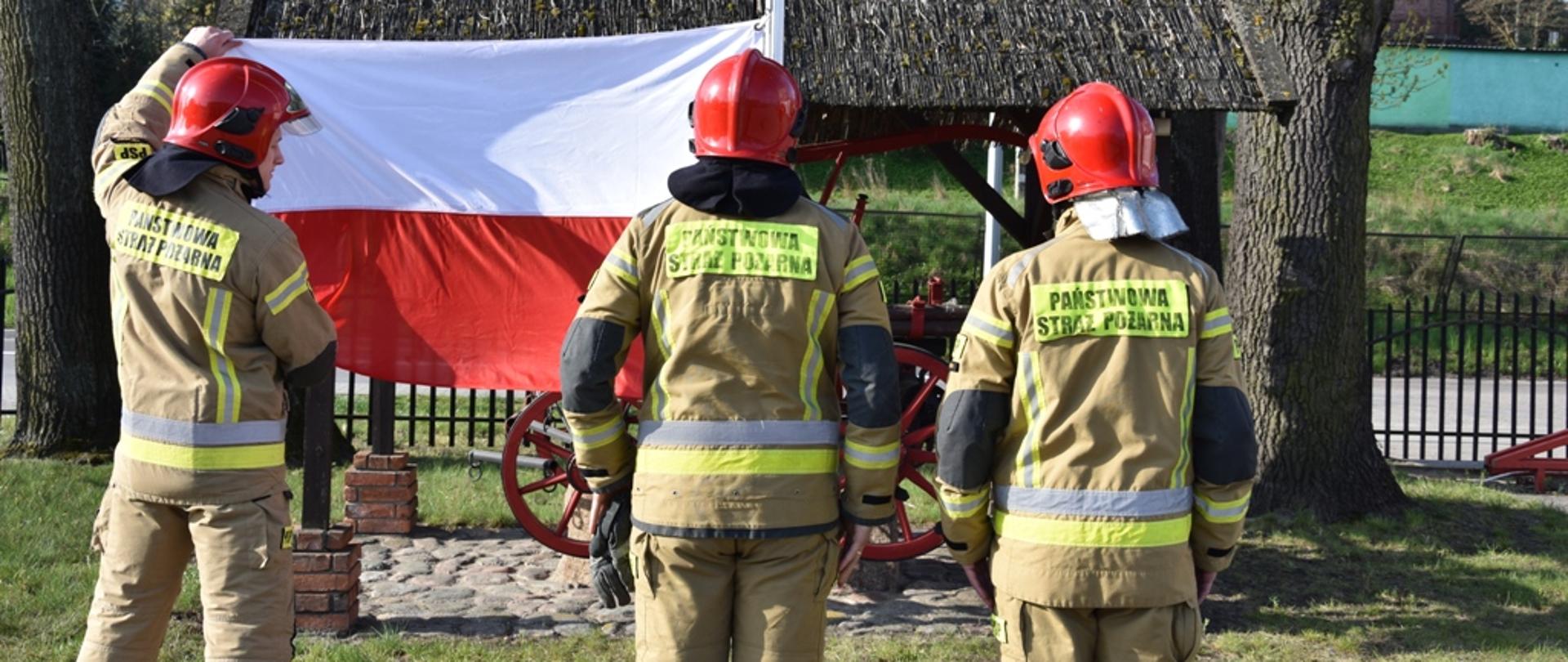 Strażacy mocują flagę do masztu. 