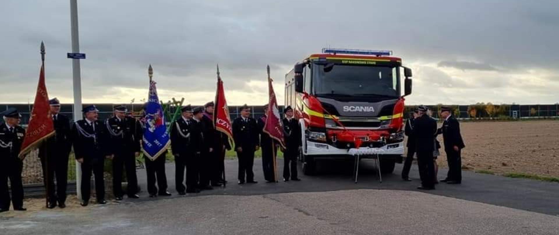 Na zdjęciu samochód ratowniczo-gaśniczy przekazywany do OSP Nakanowo Stare. Obok niego strażacy OSP ze sztandarami.