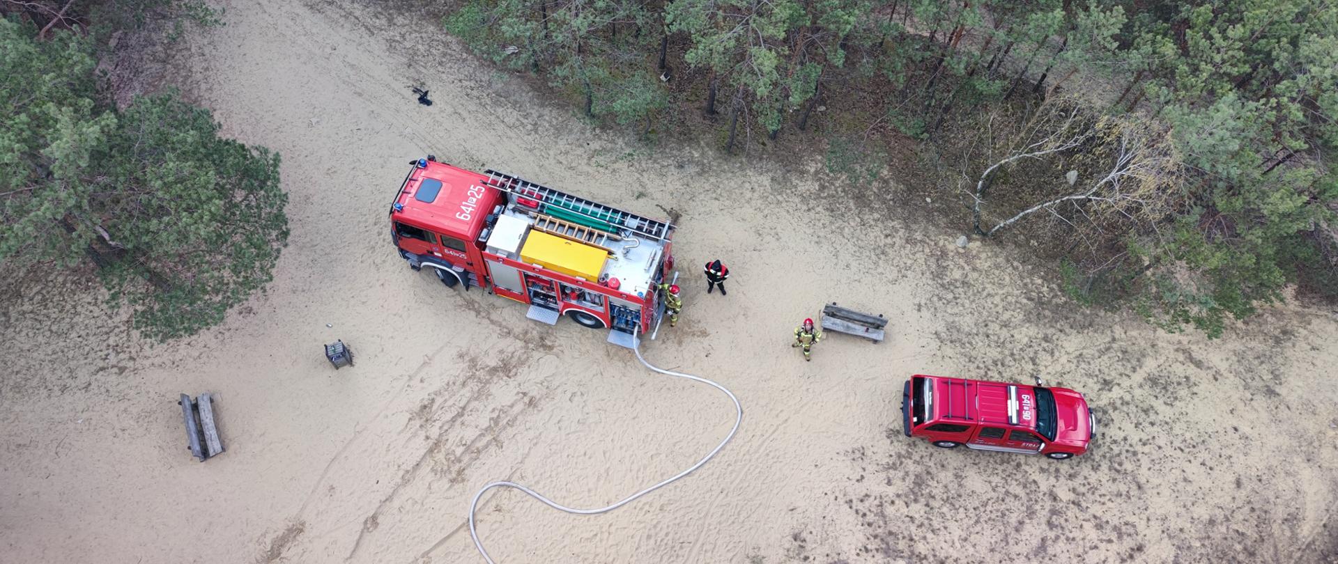 Widok z góry. Samochody pożarnicze, strażacy, rozwinięte węże.
