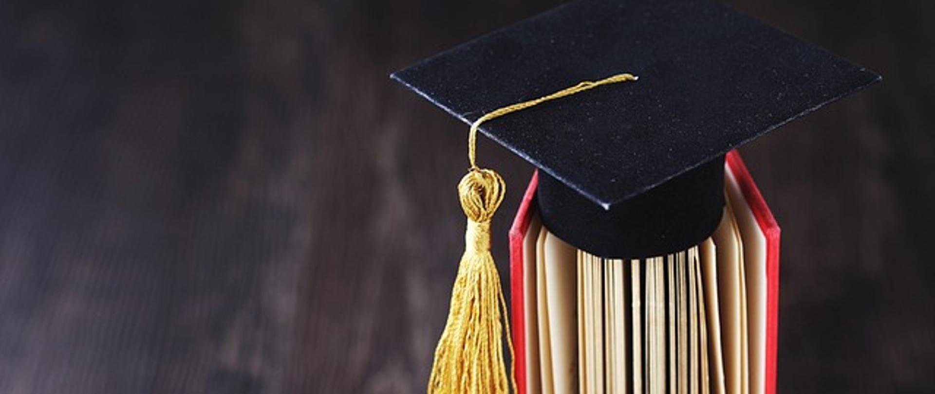 Zdjęcie biretu absolwenta ułożonego na książce