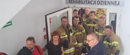 Na zdjęciu widoczni są strażacy, którzy uczestniczą w rozpoznaniu obiektu. Strażacy wychodzą z oddziału rehabilitacji dziennej.