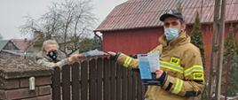 Dystrybucja ulotek. Strażacy wręczają ulotki na temat szczepień mieszkaniom powiatu.