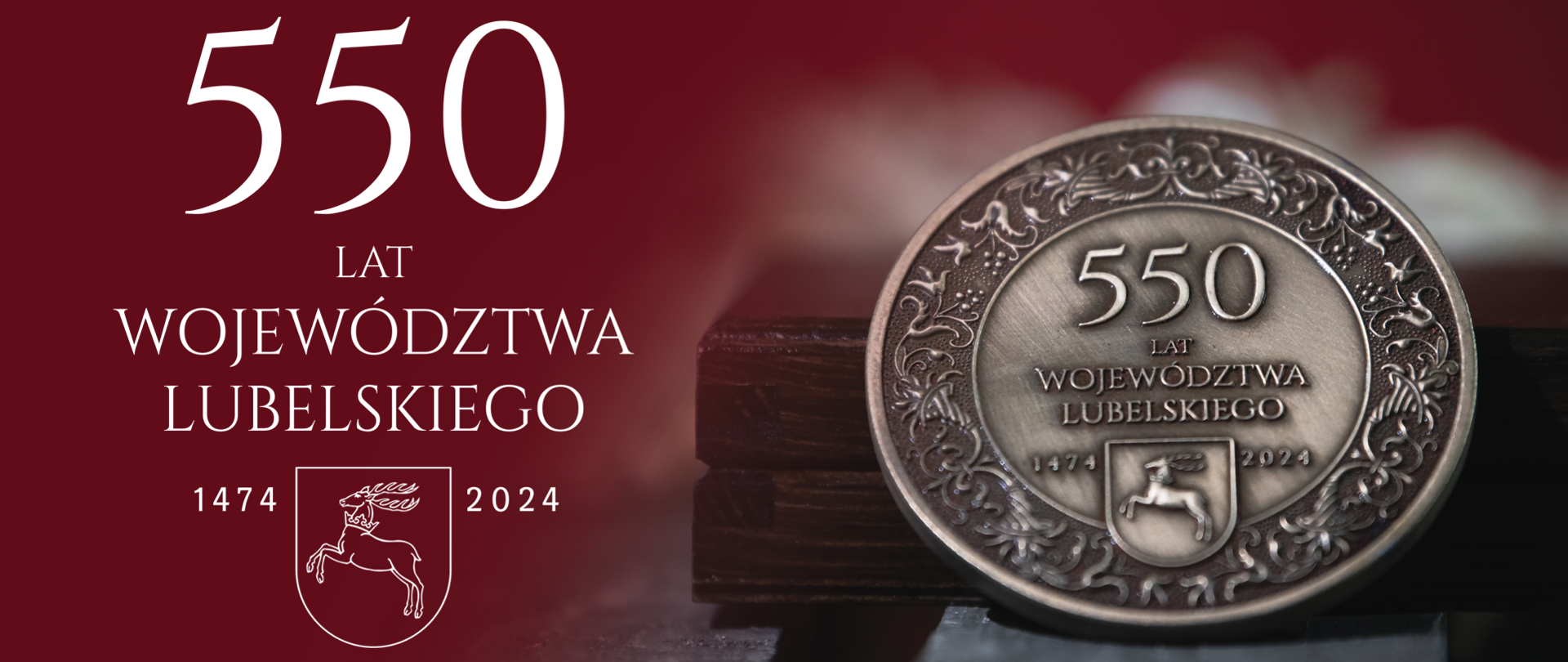 Na bordowo-czarnym tle po lewej stronie napis 550-lecia Województwa Lubelskiego wraz z godłem województwa, po prawej stronie medal oparty o ramkę