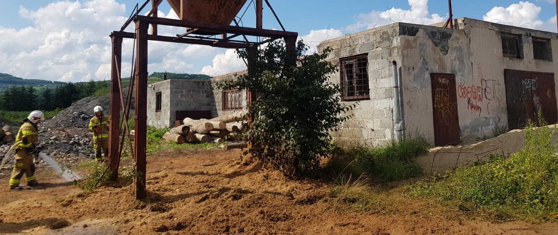 Strażacy gaszą pożar trocin wysypanych z silosa.