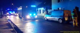 W miejscowości Jasień przy ul. Żarska w budynku jednorodzinnym powstał pożar. Na ulicy stoją samochody strażackie z Jednostki Ratowniczo-Gaśniczej w Lubsku i samochód Pogotowia gazowego. Jest późny wieczór.