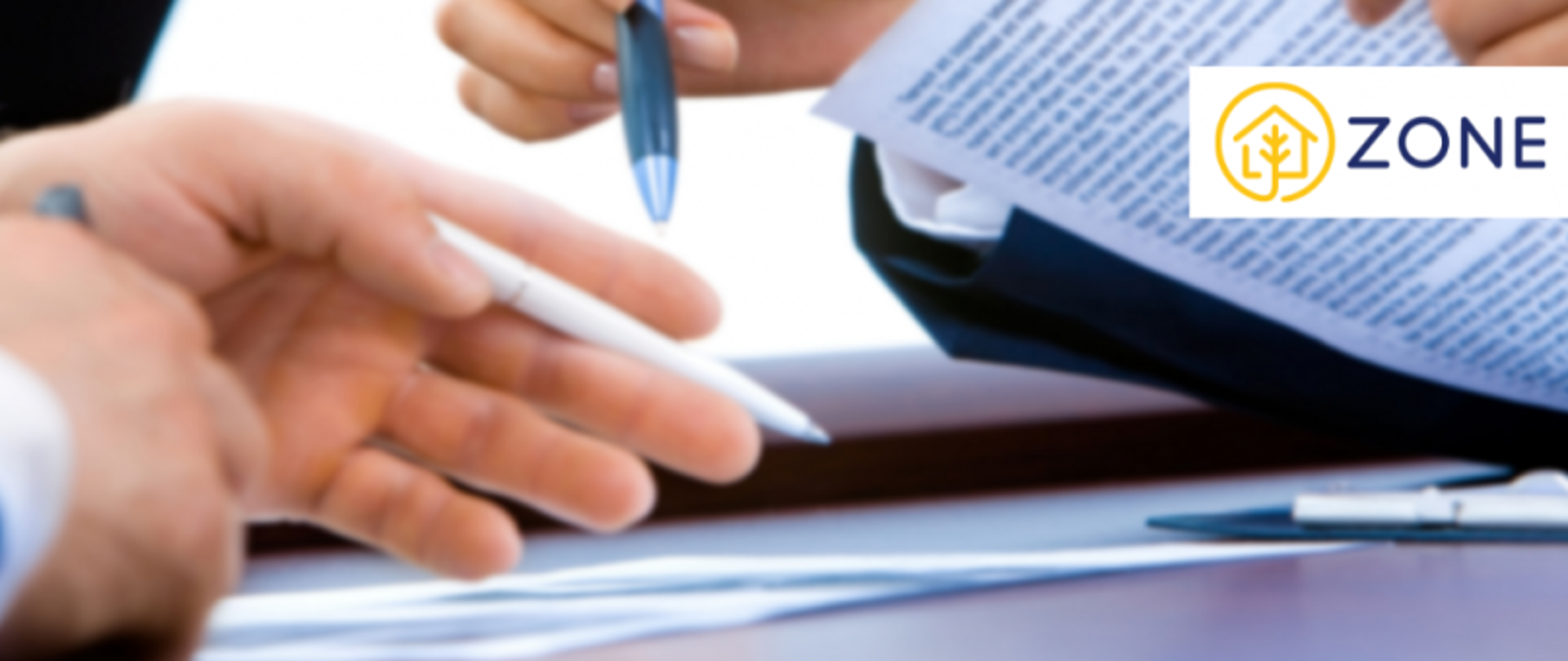 Zbliżenie na trzy dłonie pracujące nad dokumentem z tekstem; logo „ZONE” z ikoną domu i drzewa w prawym górnym rogu.