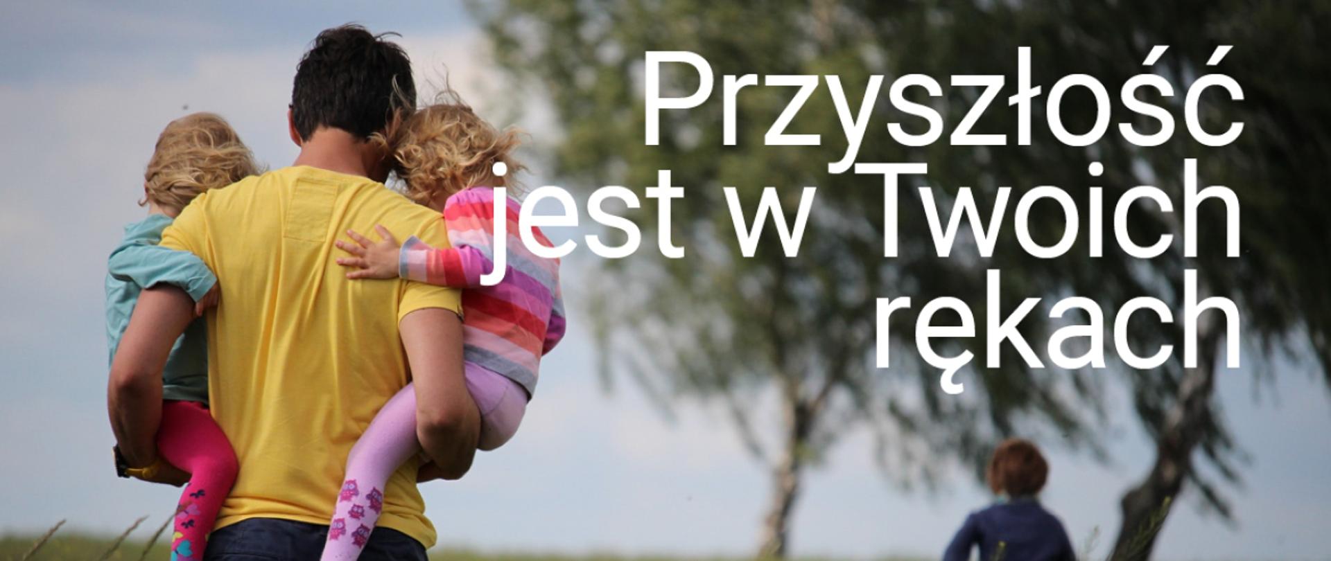 Mężczyzna trzyma w ramionach dwie dziewczynki, przed nimi biegnie chłopiec. Napis "Przyszłość jest w Twoich rękach"