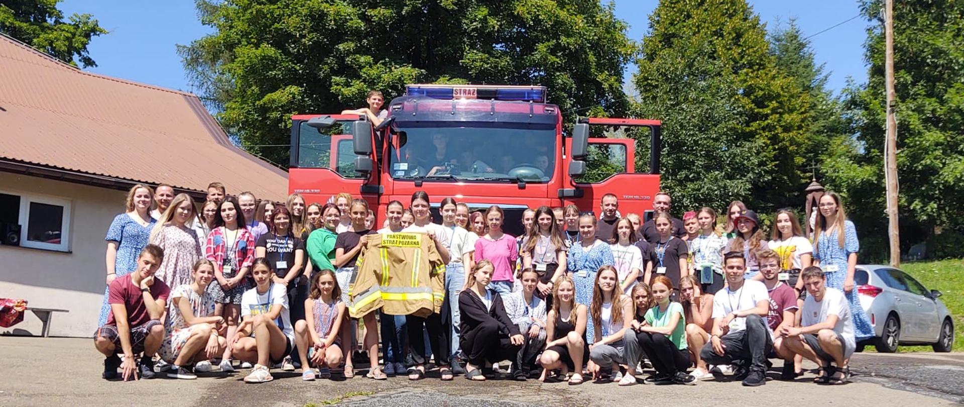 Dzieci i młodzież na tle samochodu pożarniczego 