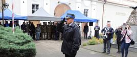 Na zdjęciu funkcjonariusz PSP w umundurowaniu wyjściowym. Zdjęcie wykonane w ciągu dnia. Funkcjonariusz oddaje honor.