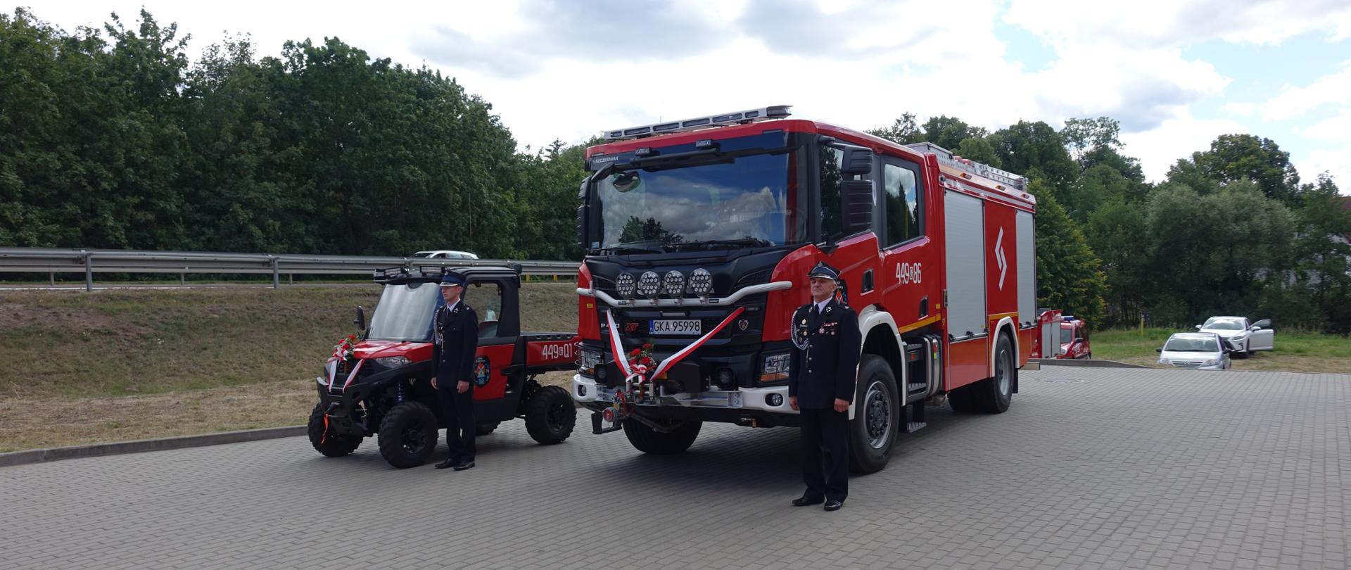 Ciężki samochód ratowniczo-gaśniczego oraz pojazdu terenowego typu UTV, przy których stoi dwóch strażaków z OSP Żukowo.