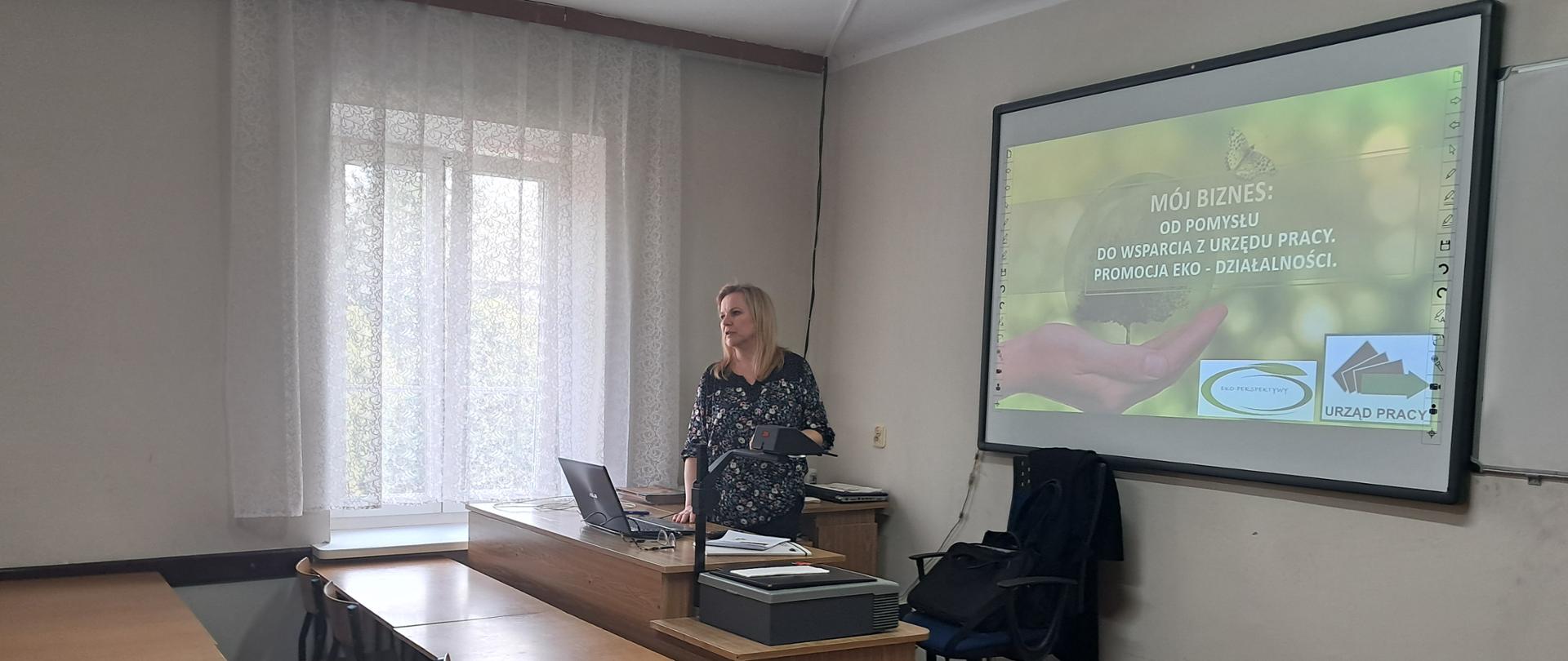 Pracownik Powiatowego Urzędu Pracy w Bielsku Podlaskim na tle prezentacji Mój biznes.