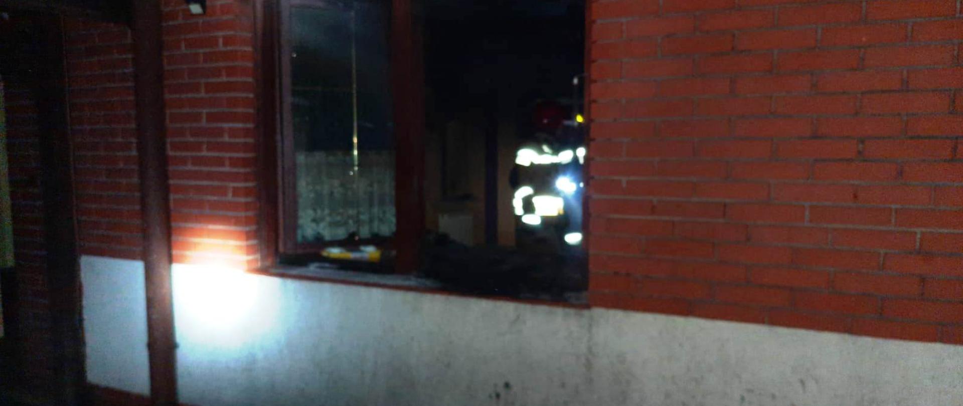 Na zdjęciu widać porze otwarte oknostrażaka znajdującego się w budynku mieszkalnym na parterze., który sprawdza kuchnię po pożarze oleju.