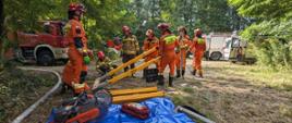 Strażacy na ćwiczeniach w trakcie sprawiania sprzętu do ćwiczeń.