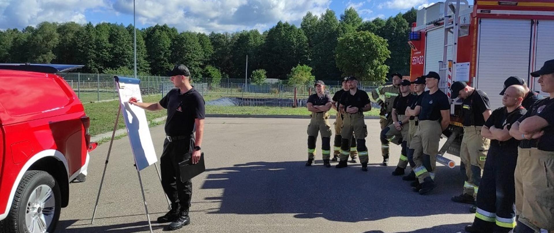 Zdjęcie przedstawia strażaków PSP i OSP z gm Wielbark podczas odprawy poprzedzającej ćwiczenia praktyczne