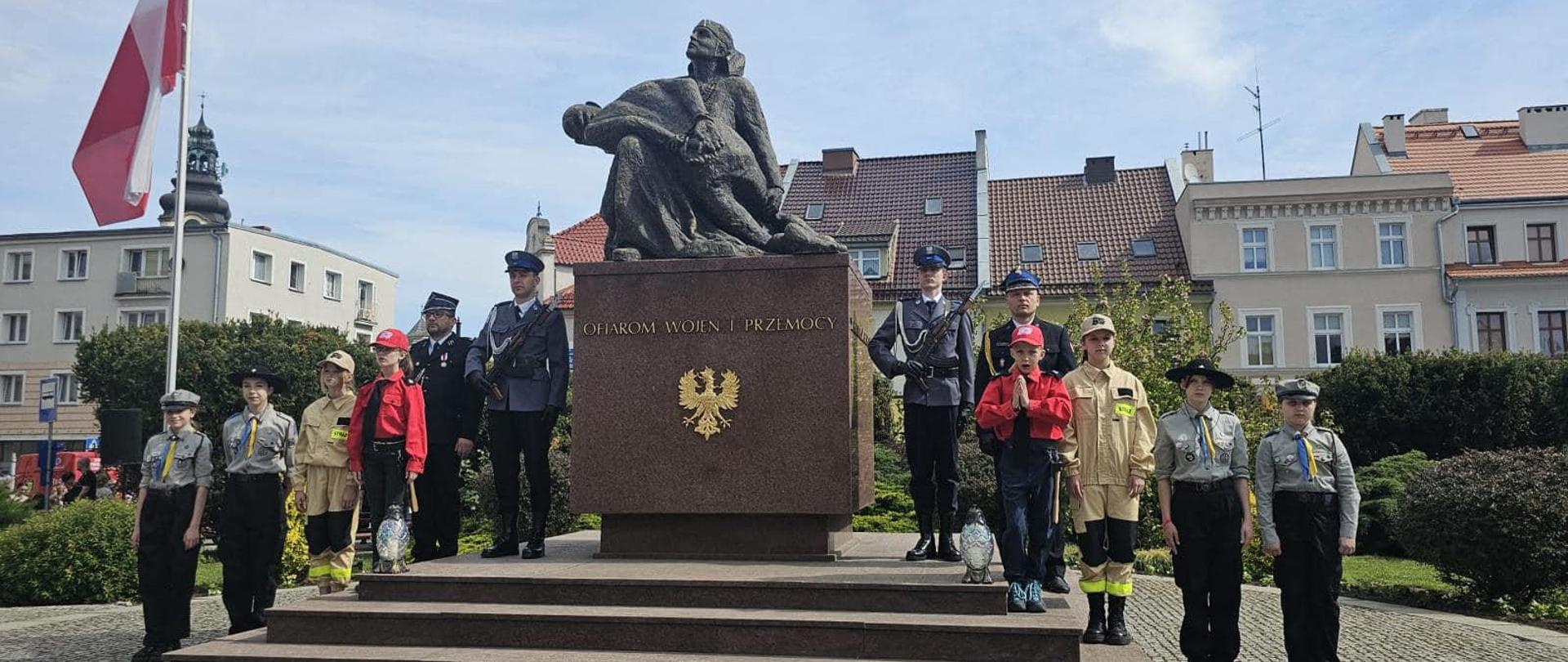 Na zdjęciu znajduje się uroczysta warta pełniona przez rożne formacje przy pomniku oraz pomnik