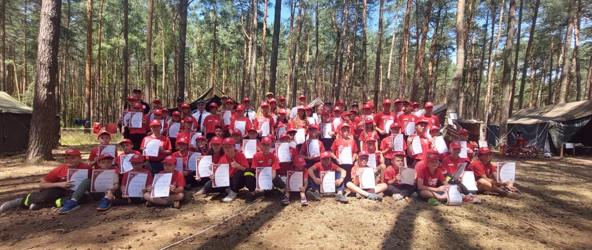 Obóz MDP Lgiń. Grupa ludzi, uczestników obozu wspólnie pozuje do pamiątkowego zdjęcia, w tle drzewa.