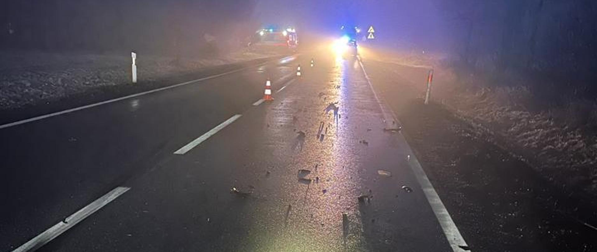na zdjęciu widać pas jezdni drogi krajowej nr 73, na drodze pozostałości po wypadku, plastiki szkło, oraz pojazdy służb ratowniczych.