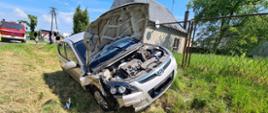 Widać samochód na skarpie, ma uszkodzoną prawą stronę i podniesioną maskę