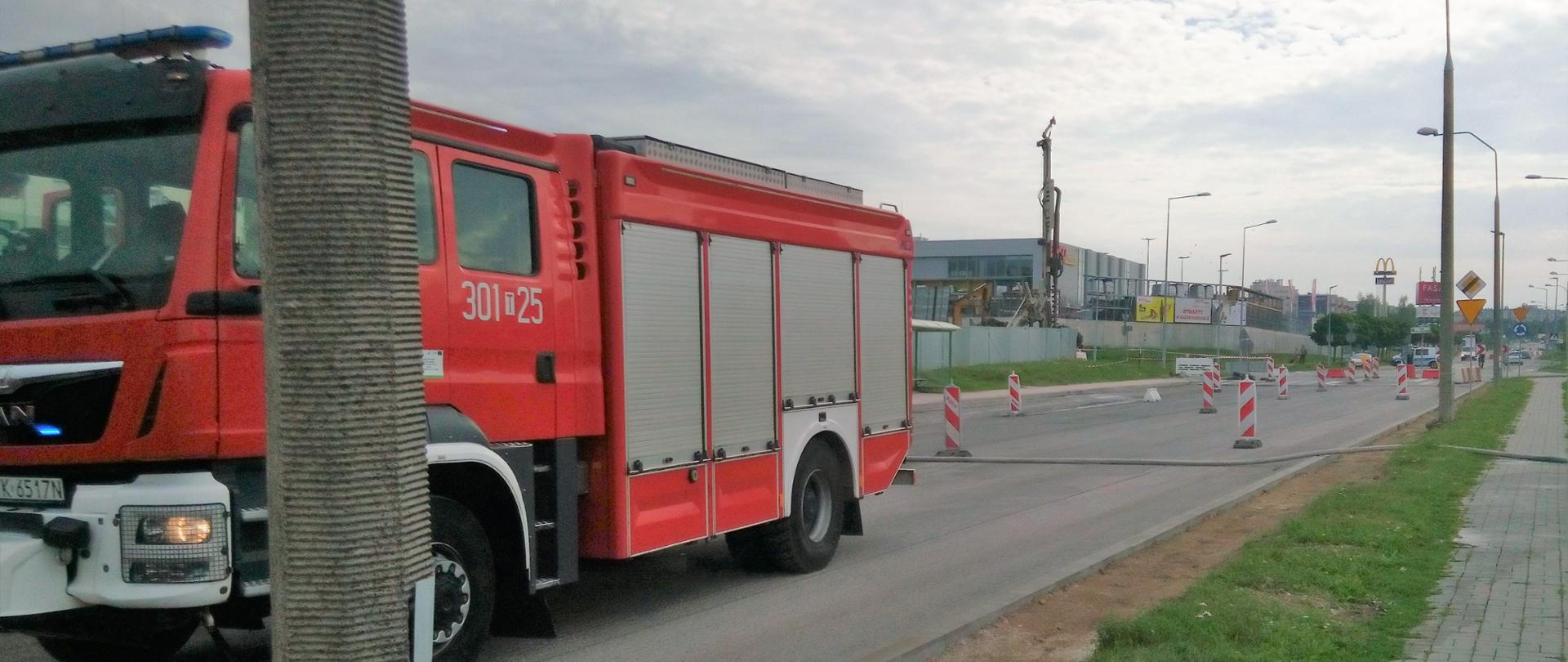 Zdjęcie przedstawia zamkniętą dla ruchu aleję Szajnowicza Iwanowa. Na pierwszym planie samochód pożarniczy, a po lewej stronie drogi widać ogrodzenie placu budowy i wiertnicę, która uszkodziła gazociąg.