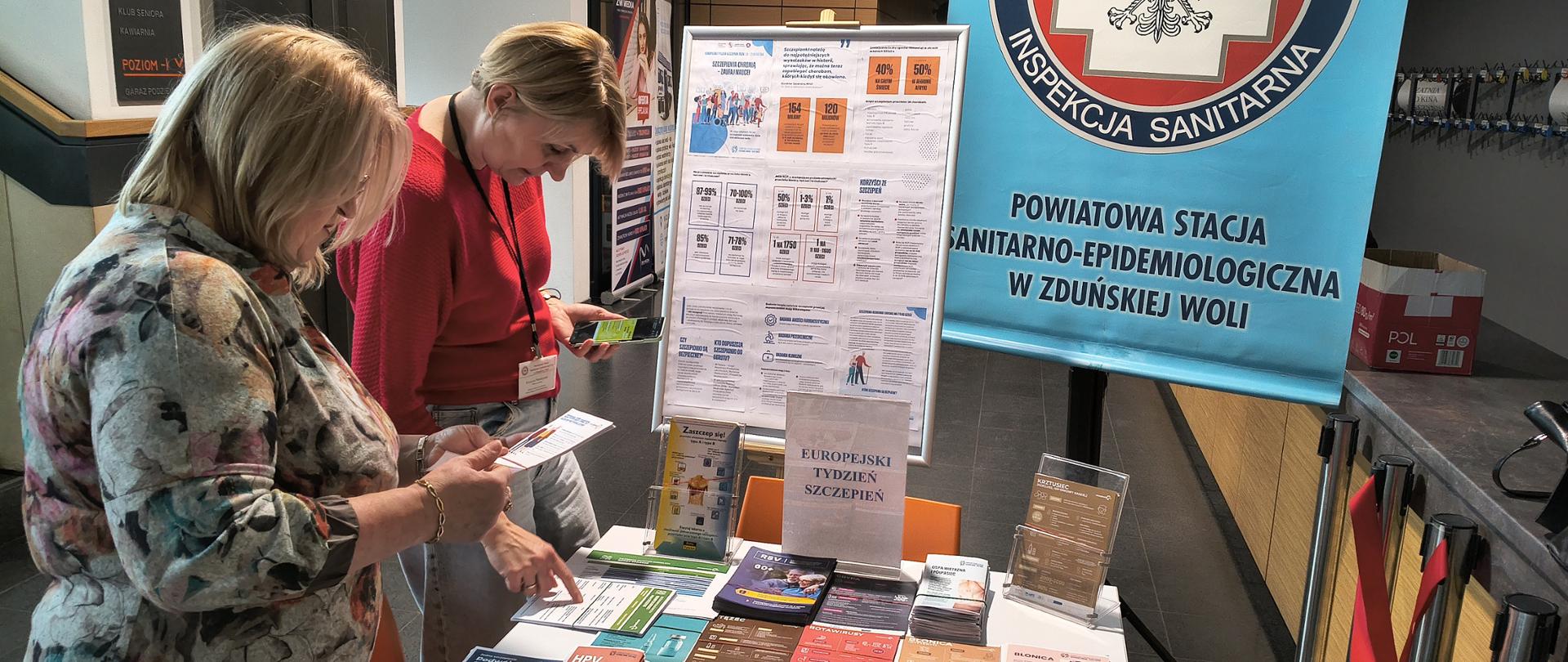 dwie kobiety stoją przy stoisku PSSE w MDK w Zduńskiej Woli w ramach Europejski Tydzień Szczepień