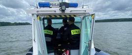 Strażacy wraz z Policją patrolujący łodzią akwen wodny.