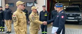 Awansowani strażacy odbierający decyzje od Komendanta. W tle strażacy z JRG