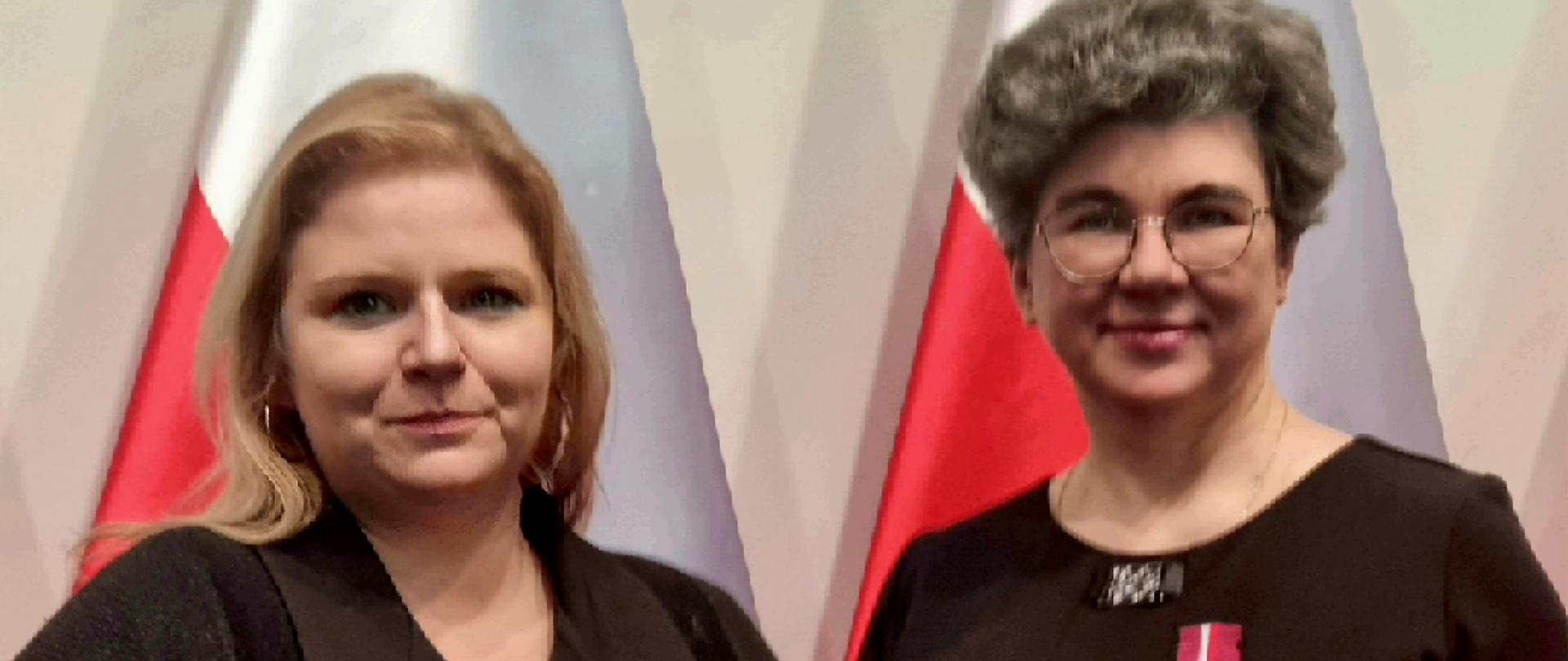 na tle flagi biało czerwonej dwie kobiety w czarnym ubraniu uśmiechnięte trzymające brązowe pudełka w których są medale