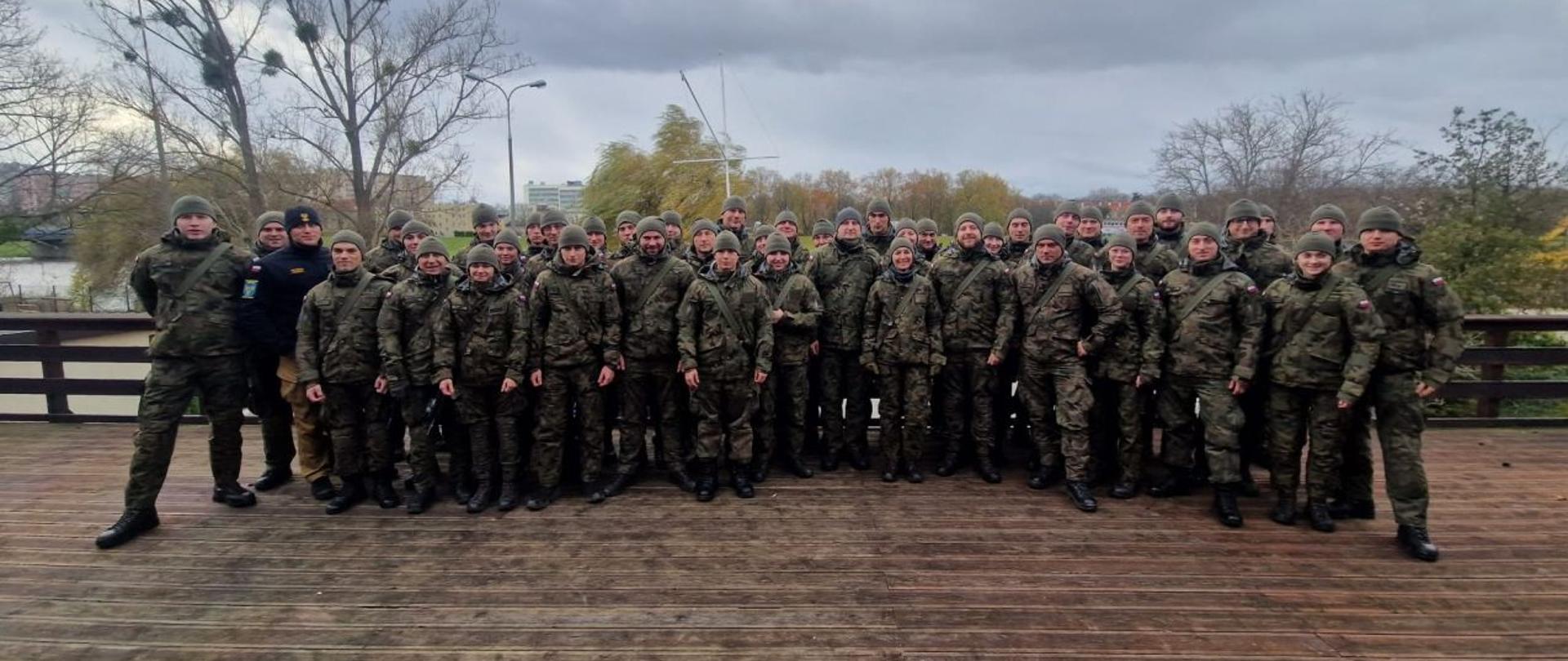 Wspólne zdjęcie umundurowanych żołnierzy Wojsk Obrony Terytorialnej oraz wykładowców z Ośrodka Szkolenia Komendy Wojewódzkiej Państwowej Straży Pożarnej. Zdjęcie na tarasie jednostki OSP ORW Opole.
