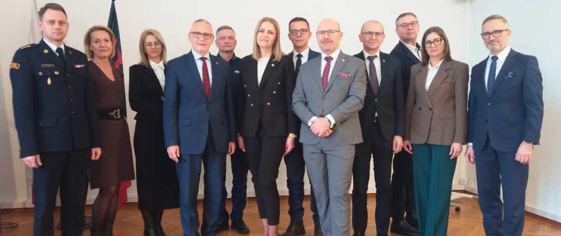 Uroczyste powołanie Państwowego Powiatowego Inspektora Sanitarnego w Wąbrzeźnie przez Państwowego Wojewódzkiego Inspektora Sanitarnego w Bydgoszczy – grupowe zdjęcie kilkunastu osób stojących w sali urzędowej, ubranych w eleganckie stroje formalne i mundur, wykonane podczas oficjalnej ceremonii.
