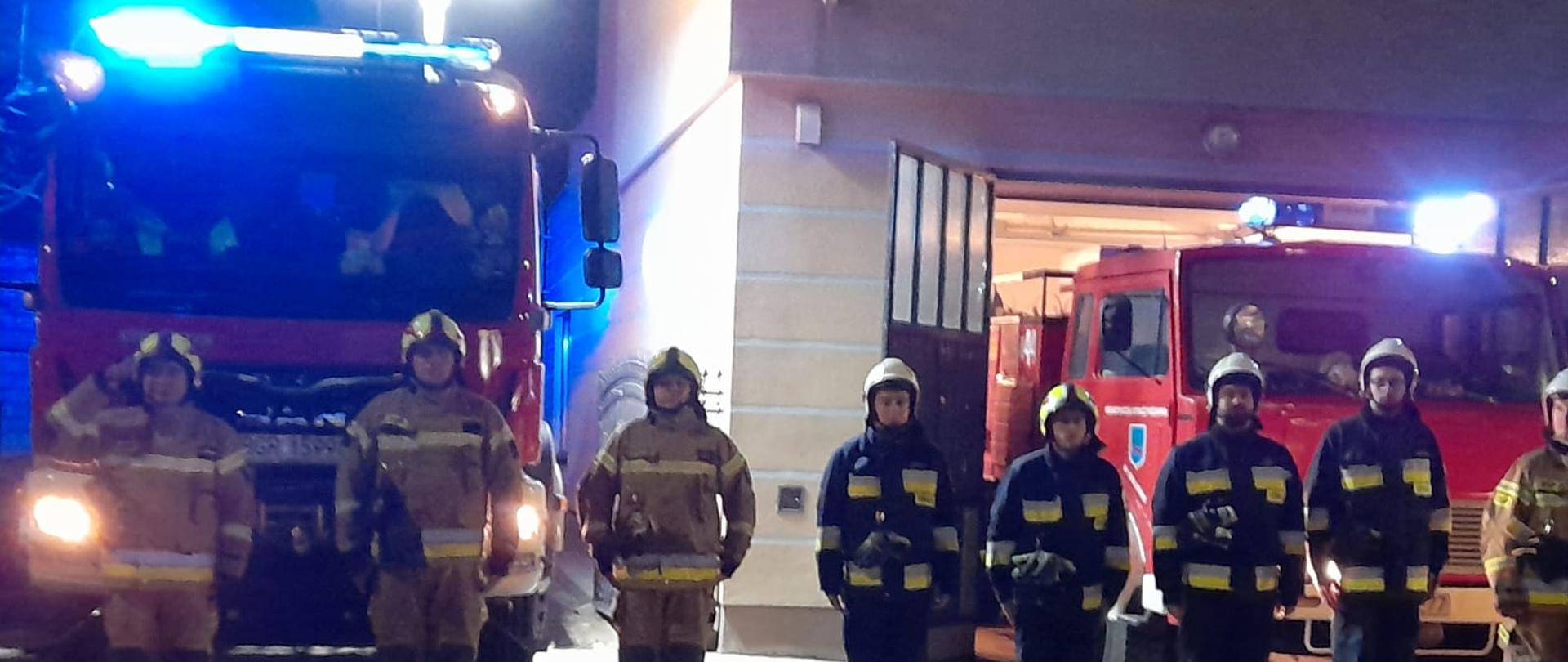 Na zdjęciu druhowie OSP Grajewo przy samochodzie z włączonym oświetleniem. Dookoła zmrok.