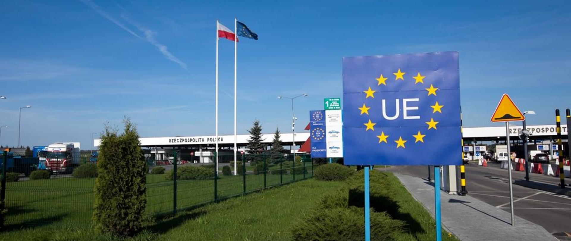 Przejście graniczne z Unią Europejską. Baner Unii Europejskiej, w tle flagi Polski i Unii Europejskiej, przejazd na samochody.