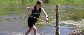 zawodniczka wychodzi z rzeki trzymając się liny asekuracyjnej