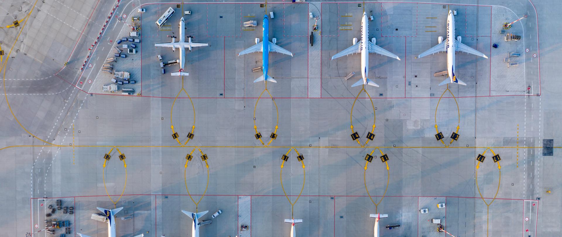 Na zdjęciu widać płytę lotniska z lotu ptaka, na płycie stoi 8 samolotów. Kolorem czerwonym oznaczone są pasy.