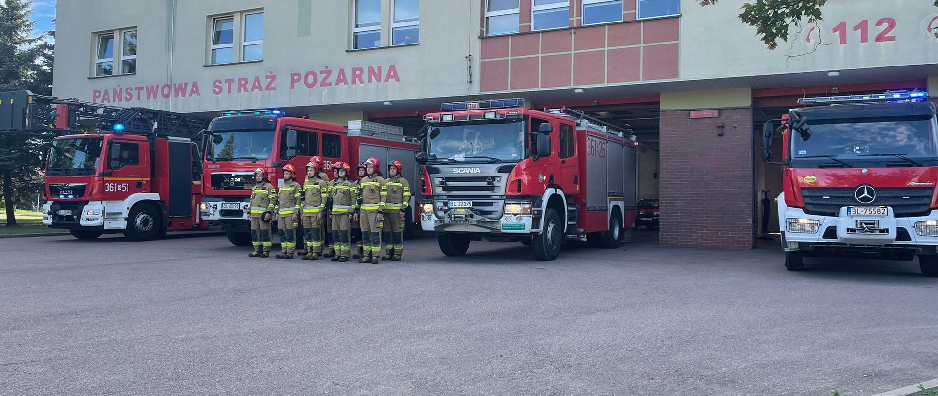 Strażacy przed Komendą Miejską PSP w Łomży oddają hołd powstańcom. w tle 4 samochody bojowe strażackie.