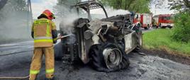 Strażak gasi maszynę rolniczą na drodze gminnej w miejscowości Datyń. Maszyna uległa uszkodzeniu w wyniku pożaru.