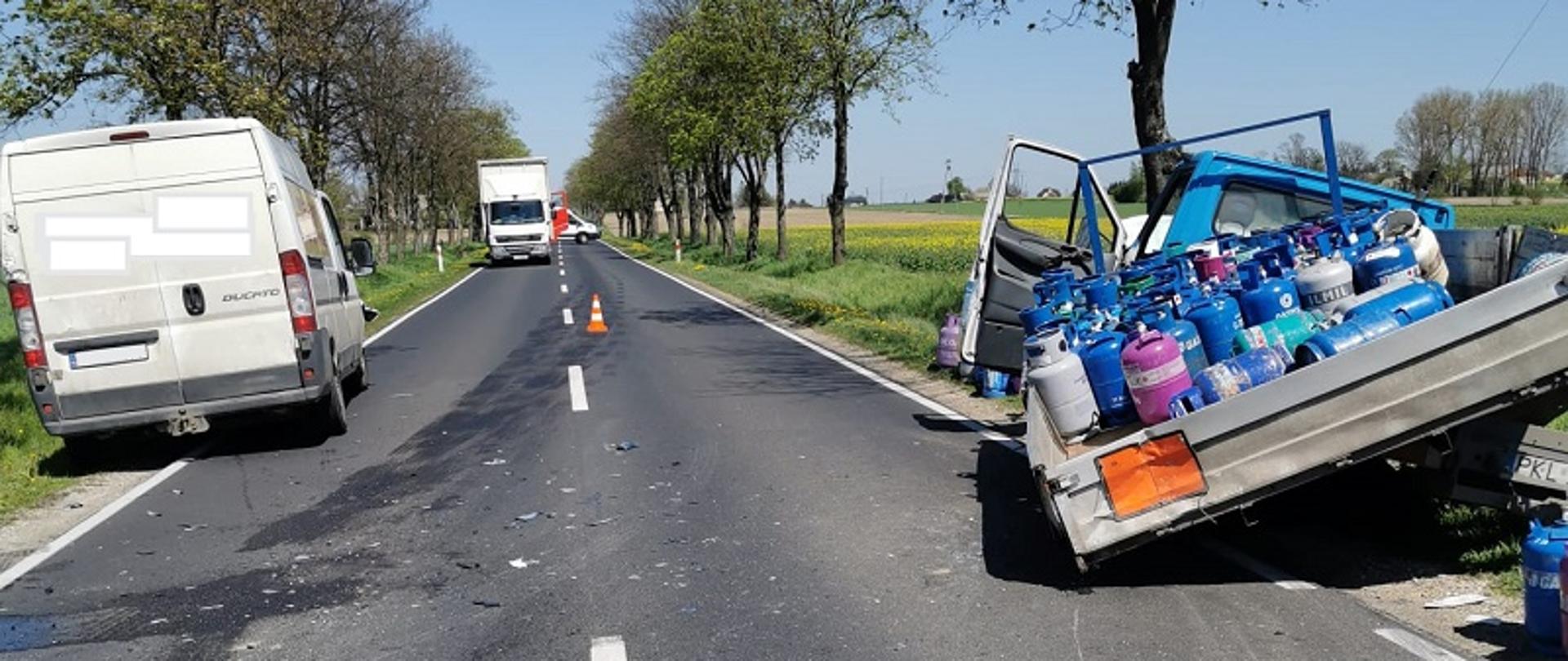 Zdjęcie przedstawia samochody dostawcze, które brały udział w zdarzeniu. Prawy samochód przewoził butle z gazem i ma uszkodzoną przestrzeń towarową.