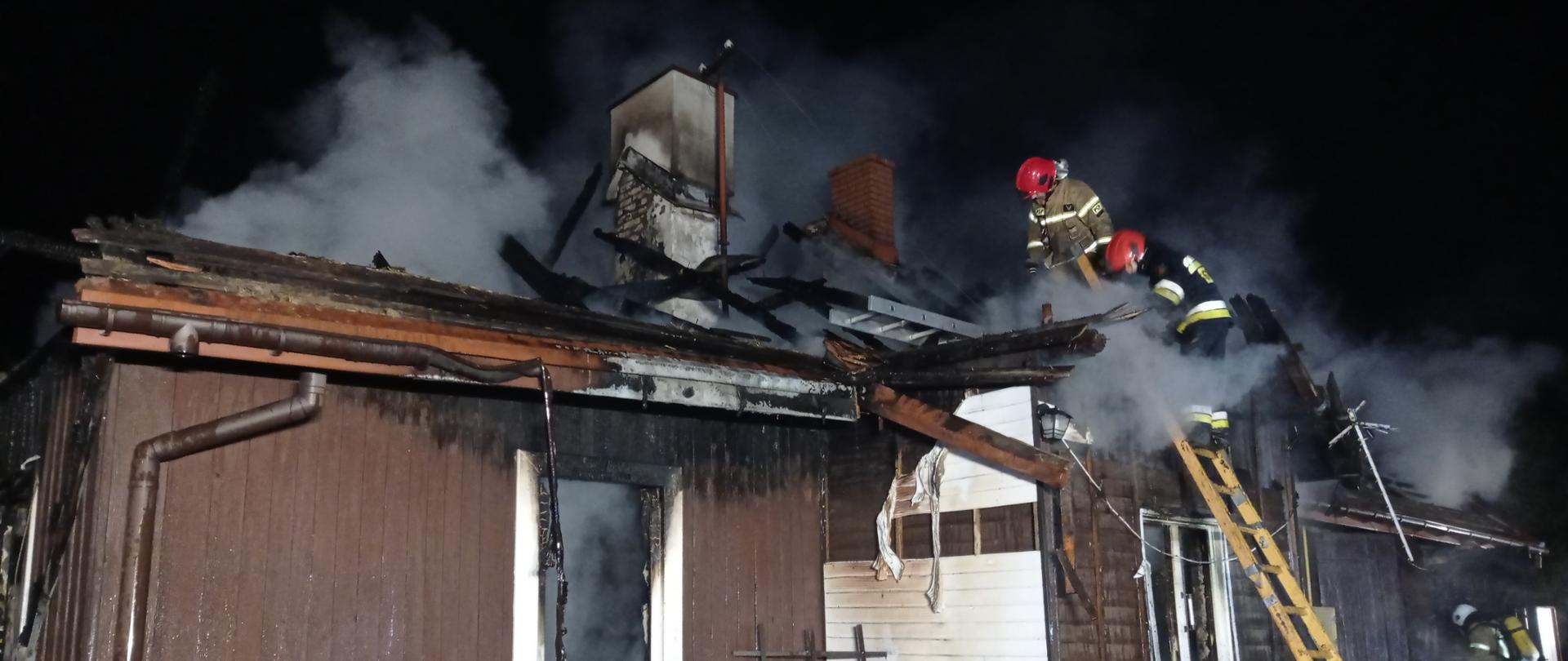 Na zdjęciu widać spalony budynek i strażaków pracujących na pogorzelisku