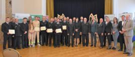 W sali widowiskowej przed sceną zasłoniętą kurtyną pozuje do zdjęcia grupa 30 osób, część z nich w czarnych mundurach – są to przedstawiciele jednostek OSP wraz z przedstawicielami instytucji – współorganizatorów wydarzenia.