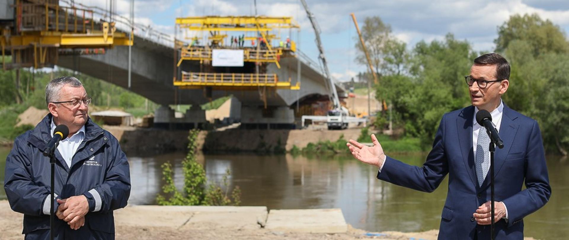 Minister Andrzej Adamczyk oraz premier Mateusz Morawiecki stoją podczas konferencji prasowej.
