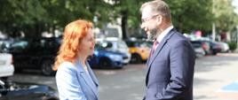 Minister funduszy i polityki regionalnej Grzegorz Puda stoi na chodniku i wita się z wicepremier Republiki Słowacji ds. planu odbudowy i funduszy europejskich Lívią Vašákovą 