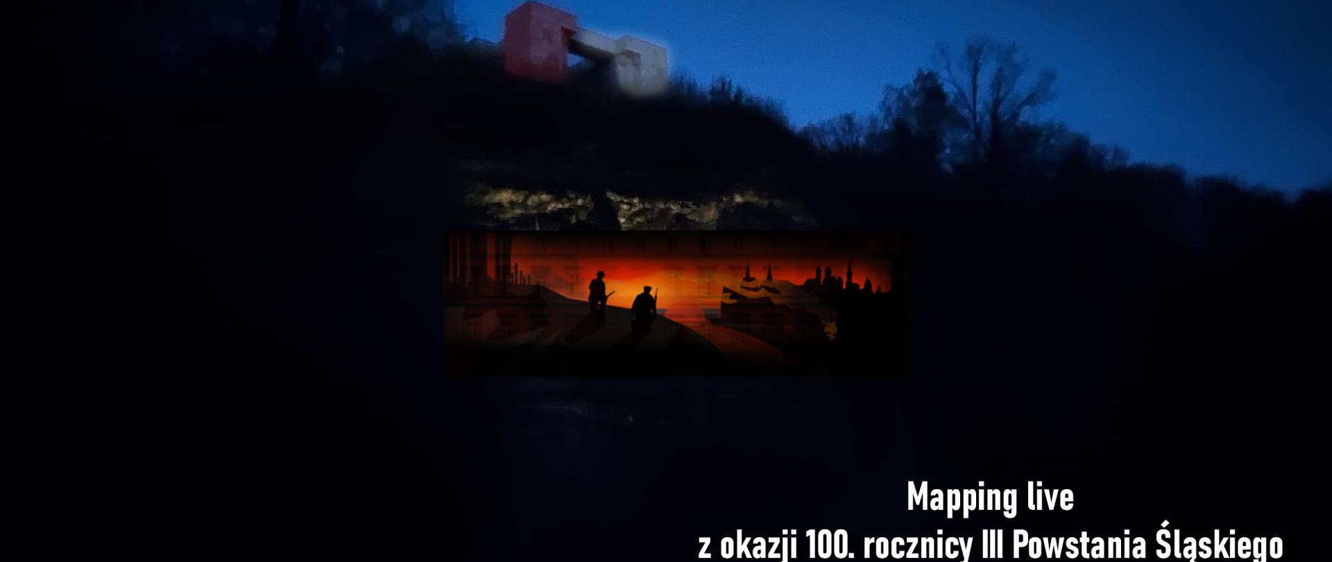 Na zdjęciu Amfiteatr Góry św. Anny z widocznym u góry Pomnikiem Czynu Powstańczego.
Pomnik podświetlony na biało-czerwono.
Dookoła czerń. Na dole po prawej informacja o projekcji mappingu. Po lewej stronie organizatorzy i ich loga