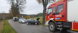 Zdjęcie przedstawia rozbity pojazd i wozy służb ratowniczych