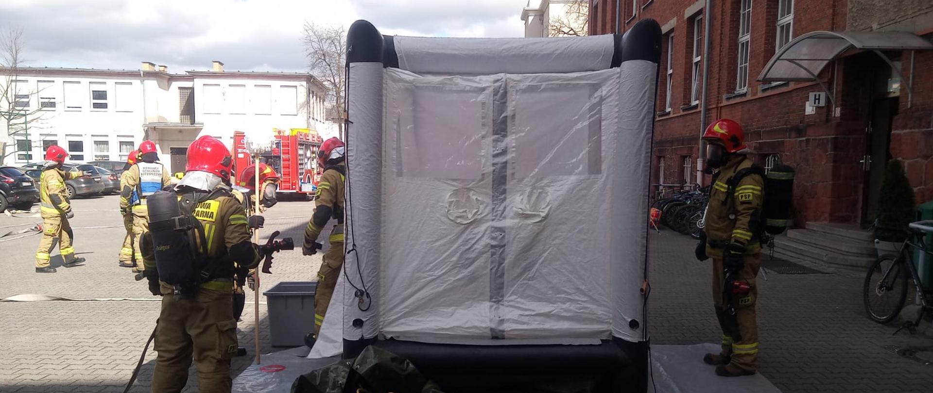 Strażacy i kabina dekontaminacyjna.