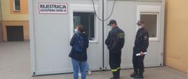 zdjęcie przedstawia funkcjonariuszy JRG w stojących przed punktem szczepień przeciwko Covid 19