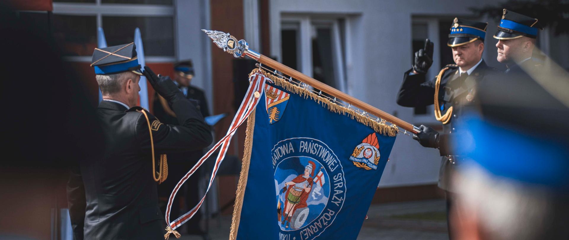 oficer salutuje przed sztandarem