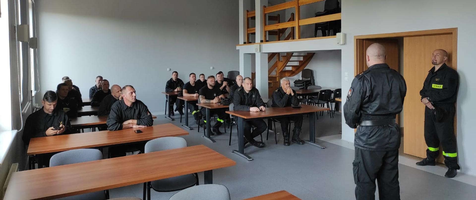 Zdjęcie przedstawia strażaków podczas zaliczenia testu wiedzy na sali konferencyjnej komendy