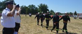 Zawody sportowo-pożarnicze w Jeziorach. Plac ćwiczeń. Trwa ocena jednej z konkurencji zawodów - musztry. Drużyna oceniana przechodzi przed komisja sędziowską. Sędziowie salutują.